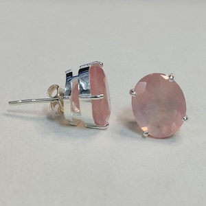 Puede incluir: Un par de pendientes de plata con piedras ovaladas de color rosa.