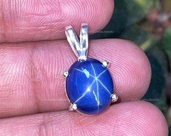 May include: A silver pendant featuring a blue star sapphire gemstone with a six-pointed star.