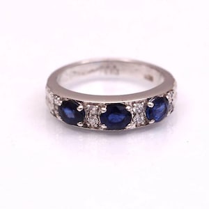 Pode incluir: Um anel de banda de prata com três safiras azuis ovais e diamantes menores engastados na banda.