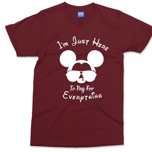 May include: Burgundy t-shirt featuring a white silhouette of Mickey Mouse wearing sunglasses and the text "I'm Just Here To Pay For Everything".