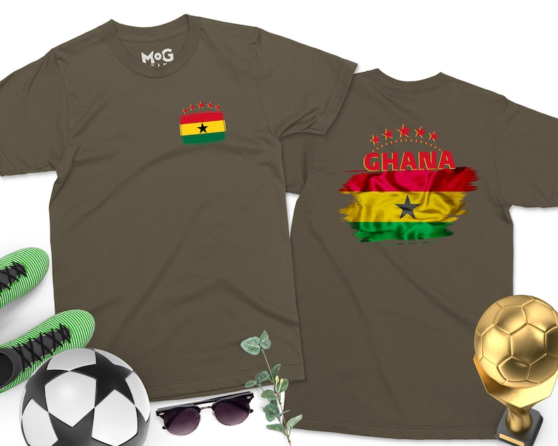 May include: Two olive green t-shirts with the flag of Ghana printed on them. One shirt has the flag on the left chest and the word "GHANA" printed below it. The other shirt has the flag on the back with five red stars above it.