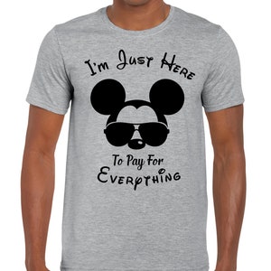 May include: A grey t-shirt featuring a black Mickey Mouse wearing sunglasses and the text "I'm Just Here To Pay For Everything".