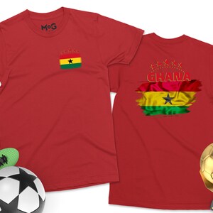 May include: Two red t-shirts with a Ghanaian flag design. One shirt has a small flag on the front and the other has a larger flag with the word "GHANA" on the back.