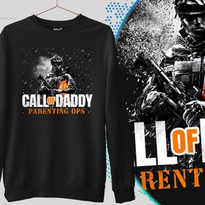 Puede incluir: Sudadera negra con un gráfico de un soldado sosteniendo un arma y el texto "Call of Daddy Parenting Ops" en naranja.