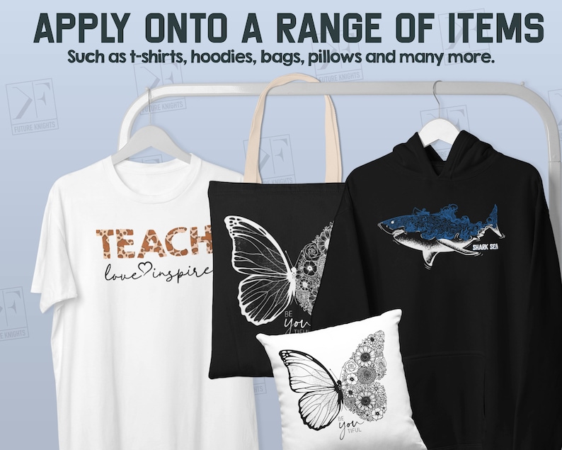 May include: A white t-shirt with the text "TEACH love inspire" in brown lettering, a black tote bag with a butterfly design, a black hoodie with a blue shark design, and a white pillow with a butterfly design. The items are hanging on a rack.