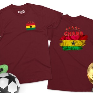 May include: Two maroon t-shirts with a Ghanaian flag design. The front shirt has a small flag with stars and the back shirt has a larger flag with the text "GHANA" in red.