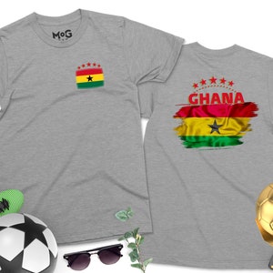 May include: Two gray t-shirts with a Ghanaian flag design. One shirt has a small flag on the front and the other has a larger flag with the word "GHANA" on the back.