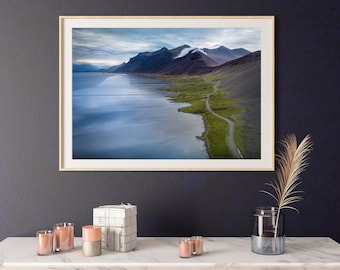 May include: A framed photograph of a scenic landscape with a winding road along a coastline. The photo features a blue body of water, green hills, and a cloudy sky.