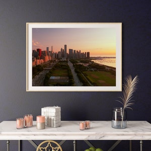 May include: A framed photograph of the Chicago skyline at sunset. The city is in the distance, with a large park in the foreground. The sky is a soft pink and orange.