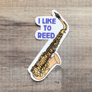 May include: A white sticker with a gold saxophone and the text "I like to reed" in purple.