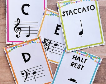 May include: A collection of white flashcards with musical notes and terms. Each card has a colorful border and a string of decorative lights at the top. The cards display notes, clefs, and terms like "Staccato" and "Half Rest."