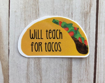May include: A taco-shaped sticker with the text "Will teach for tacos" in black. The taco has a yellow shell and is filled with green lettuce and red tomatoes. The sticker is on a light wood grain background.