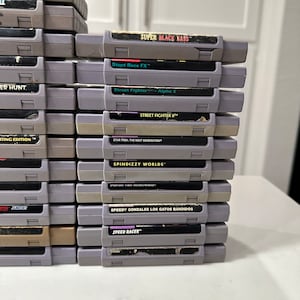 May include: A stack of 18 Super Nintendo Entertainment System (SNES) game cartridges, including titles like "Super Black Bass", "Stunt Race FX", "Street Fighter II", "Star Trek: The Next Generation", "Spindizzy Worlds", "Speedy Gonzales Los Gatos Bandidos", and "Speed Racer".