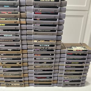 May include: A stack of vintage Super Nintendo Entertainment System (SNES) game cartridges, including titles like "Sonic Blast Man", "R-Type III", "Primal Rage", "Street Fighter II", and "Power Rangers The Fighting Edition".