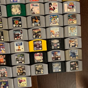 May include: A collection of 30 Nintendo 64 video game cartridges, including titles like "Rayman 2", "Star Wars: Rogue Squadron", "South Park", "Turok", and "Zelda: Ocarina of Time".