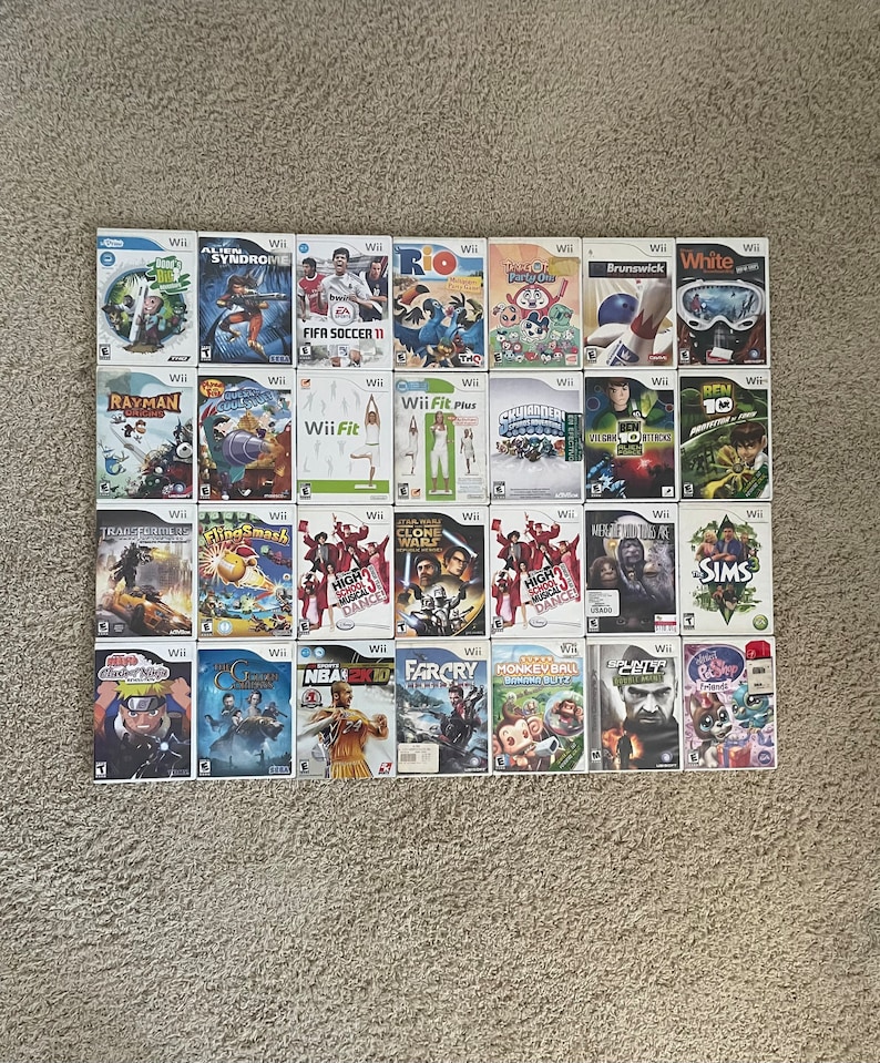 May include: A collection of 24 video game cartridges for the Nintendo Wii console. The cartridges are arranged in four rows of six. The games include titles such as Rayman, FIFA Soccer 11, Wii Fit, and High School Musical.