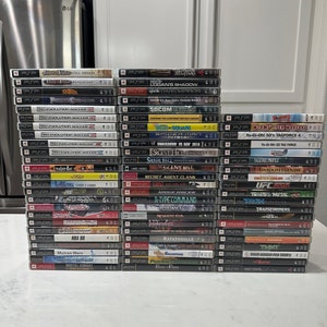 Puede incluir: Una pila de 40 cajas de juegos de video para la consola Sony PlayStation Portable (PSP). Las cajas están dispuestas en una pila vertical, con los lomos hacia afuera. Los juegos incluyen títulos como "Resistance", "Silent Hill", "Spider-Man", "Ratatouille", "Mytran Wars" y "Mortal Kombat".