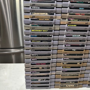 May include: A stack of vintage Super Nintendo Entertainment System (SNES) game cartridges, including titles like Mickey Mania,  Mecarobot Golf, Mario Paint, Mario is Missing!, Lethal Weapon, and Pac-Man 2: The New Adventures.
