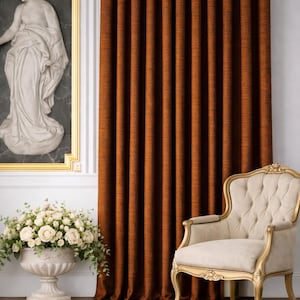 Peut inclure: Intérieur d'une pièce avec un rideau couleur rouille, plissé verticalement. Un fauteuil crème avec des détails dorés est à droite. Une œuvre d'art en marbre et un vase blanc avec des fleurs sont également visibles.