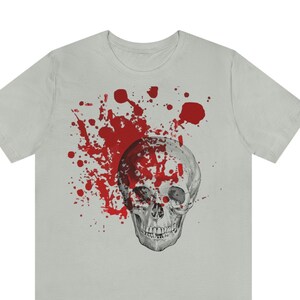 May include: A grey t-shirt with a graphic of a white skull with red blood splatter.