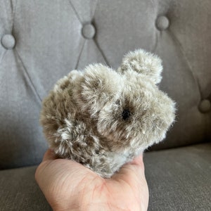 May include: A small, brown, furry stuffed animal shaped like a rabbit. The rabbit has long ears and a fluffy tail.