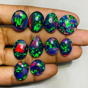 Peut inclure: Assortiment de dix cabochons d'opale noire de forme ovale et en goutte, aux couleurs iris&eacute;es vertes, bleues et rouges.