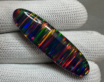 May include: A black opal cabochon with a striated pattern of iridescent colors, including red, orange, yellow, green, blue, and purple.