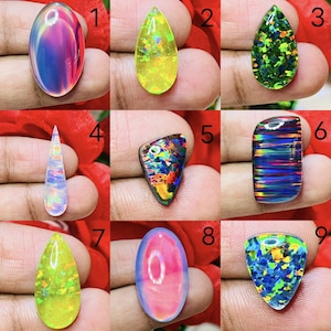 Könnte beinhalten: Neun polierte Opal-Edelsteine in verschiedenen Formen und Farben. Die Opale zeigen eine Reihe von schillernden Farbtönen, darunter Blau, Grün, Gelb und Rosa. Jeder Stein ist einzigartig, mit Mustern und Farbblitzen.