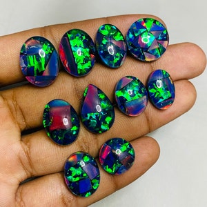 Peut inclure: Assortiment de dix cabochons d'opale noire de forme ovale et en goutte avec des reflets iris&eacute;s verts, bleus et rouges. Les pierres sont serties en mosa&iuml;que.