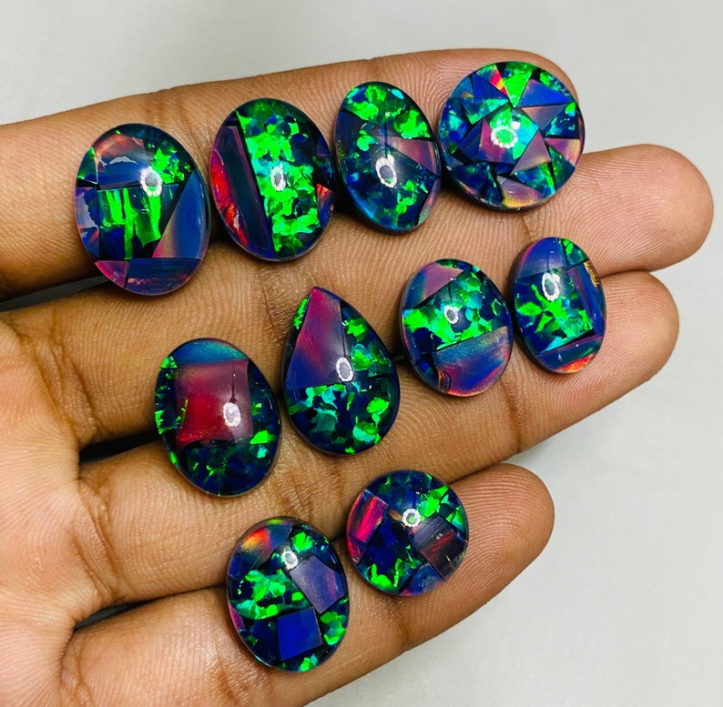 Peut inclure: Assortiment de dix cabochons d'opale noire de forme ovale et en goutte avec des reflets iris&eacute;s verts, bleus et rouges. Les pierres sont serties en mosa&iuml;que.