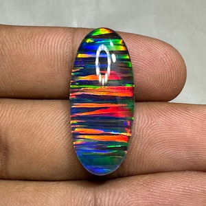 May include: Oval-shaped, iridescent opal cabochon with a rainbow of colors, including red, orange, yellow, green, blue, and purple. The opal has a black base and a striated pattern.