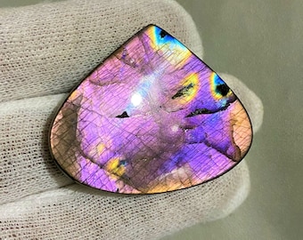 May include: A triangular iridescent labradorite gemstone with a purple, blue, and yellow color scheme. The stone has a unique, textured surface.