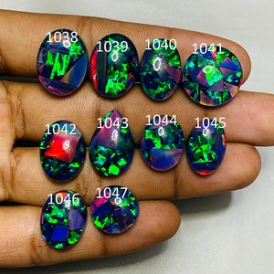 Peut inclure: Une collection de 10 opales noires de forme ovale et en goutte avec des reflets iris&eacute;s verts, rouges et bleus. Les opales sont num&eacute;rot&eacute;es de 1038 &agrave; 1047.