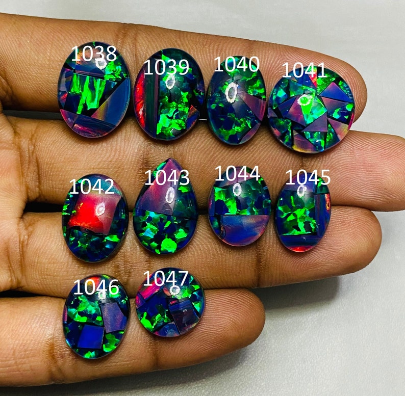 Peut inclure: Une collection de 10 opales noires de forme ovale et en goutte avec des reflets iris&eacute;s verts, rouges et bleus. Les opales sont num&eacute;rot&eacute;es de 1038 &agrave; 1047.