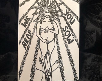May include: Monochrome art print depicting a stylized figure with a skull-like face and wheat-like hair. The figure is pregnant, with the text "WE REAP YOU SOW" radiating outwards. The artwork is on a white background.