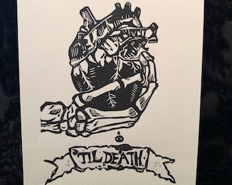 Puede incluir: Grabado en linóleo en blanco y negro de una mano esquelética sosteniendo un corazón humano con las palabras "Til Death" en una pancarta debajo.