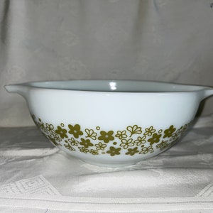 以下が含まれることがあります： 緑色の花柄の白いミキシングボウル。ボウルは幅広の縁と2つの注ぎ口があります。