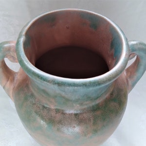 May include: A green and brown ceramic vase with two handles. The vase has a mottled glaze and a rounded body.