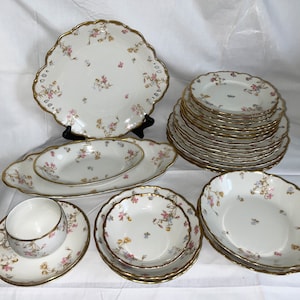 May include: A set of vintage floral china dinnerware with a delicate floral pattern in shades of pink, blue, and gold. The set includes a large platter, a serving bowl, a set of dinner plates, a set of salad plates, a set of soup bowls, and a teacup and saucer.