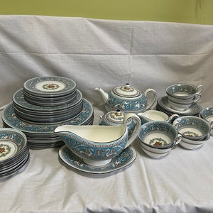 Peut inclure: Un ensemble de vaisselle en porcelaine bleu et blanc avec un motif floral. L'ensemble comprend des assiettes, des bols, une théière, un pot à crème, un sucrier et des tasses à thé et des soucoupes.