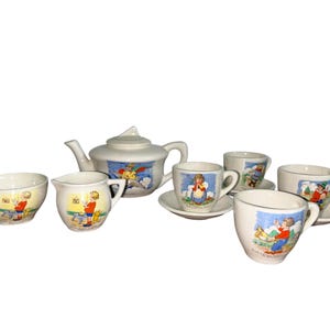 May include: A vintage children's tea set with a white teapot, creamer, sugar bowl, and four cups. Each piece features a colorful illustration of a child.