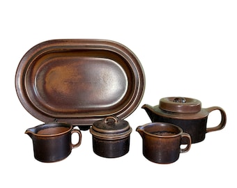 May include: A brown stoneware tea set with a teapot, creamer, sugar bowl, and oval serving platter. The set has a rustic, earthy look.
