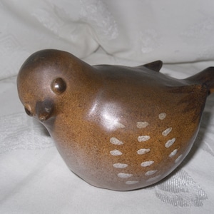 以下が含まれることがあります： 白い斑点のある茶色の陶器製の鳥の置物。鳥は下を向いており、小さなくちばしがあります。