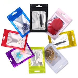 May include: A selection of colourful, clear plastic zip-top bags containing various items. The bags are in shades of blue, red, purple, green, yellow, pink, and white. Contents include jewellery, accessories, and small tools. Each bag has a hang hole.