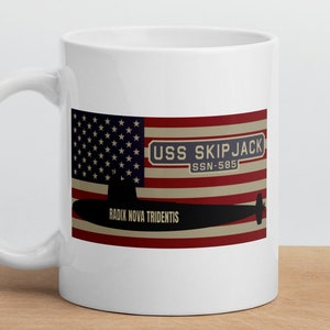 May include: White ceramic mug with a graphic of the USS Skipjack submarine, a US flag, and the text "USS SKIPJACK SSN-585 RADIX NOVA TRIDENTIS".