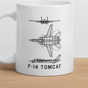 May include: White ceramic mug with a black line drawing of an F-14 Tomcat fighter jet in three different views. The text "F-14 TOMCAT" is printed below the drawings.