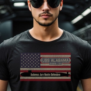 Könnte beinhalten: Ein schwarzes T-Shirt mit einem abgenutzten amerikanischen Flaggen-Design, das eine U-Boot-Silhouette und den Text "USS ALABAMA SSN-731 Audemus Jura Nostra Defendere" zeigt.
