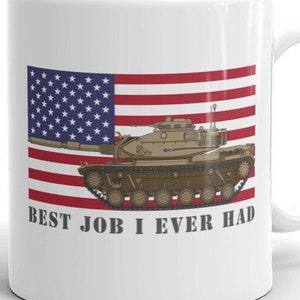 May include: White ceramic mug featuring a graphic of a tank driving in front of an American flag. The text "BEST JOB I EVER HAD" is printed below the image.