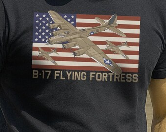 May include: A navy blue t-shirt featuring a graphic of a B-17 Flying Fortress aircraft against an American flag. The shirt is worn with khaki pants and a brown belt. A vintage military aircraft is in the background.