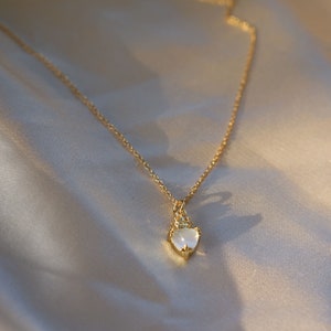 May include: A gold chain necklace with a heart-shaped pendant featuring a white stone and a crown design.